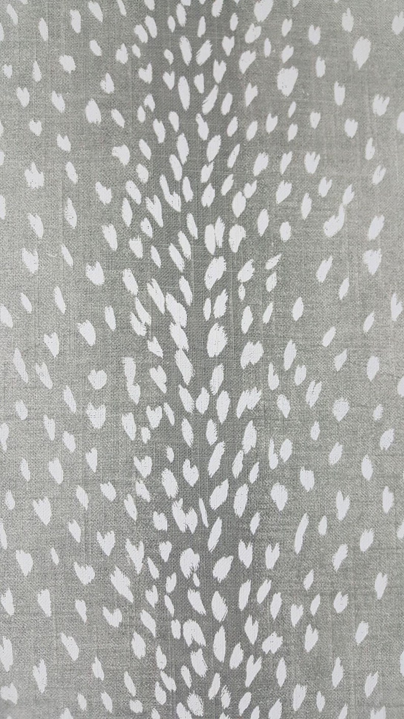 May include: A close-up of a gray fabric with a white, abstract, speckled pattern. The pattern resembles a deer's spots.