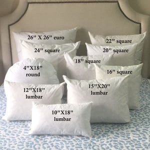 May include: A collection of white pillow inserts in various sizes and shapes, including euro, square, and lumbar. The pillows are arranged on a white and blue patterned bedspread.