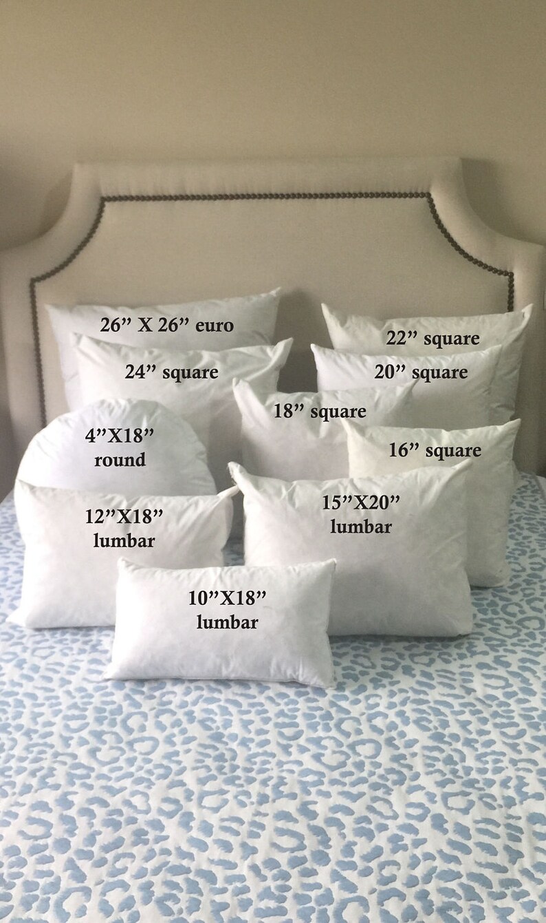 May include: A collection of white pillow inserts in various sizes and shapes, including euro, square, and lumbar. The pillows are arranged on a white and blue patterned bedspread.