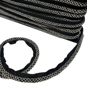 May include: Black and white braided trim with a diamond pattern. The trim is made of a soft, flexible material and is perfect for adding a touch of elegance to any project.