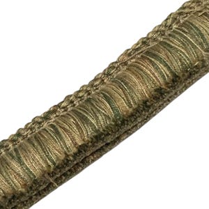 May include: Close-up of decorative trim with a textured, fringed edge. The trim features a combination of olive green, tan, and brown colors. The trim is likely used for upholstery or other decorative purposes.