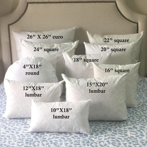 May include: A collection of white pillow inserts in various sizes and shapes, including square, round, and lumbar. The pillow inserts are arranged on a white and blue patterned bedspread. The sizes of the pillows are labeled in inches.