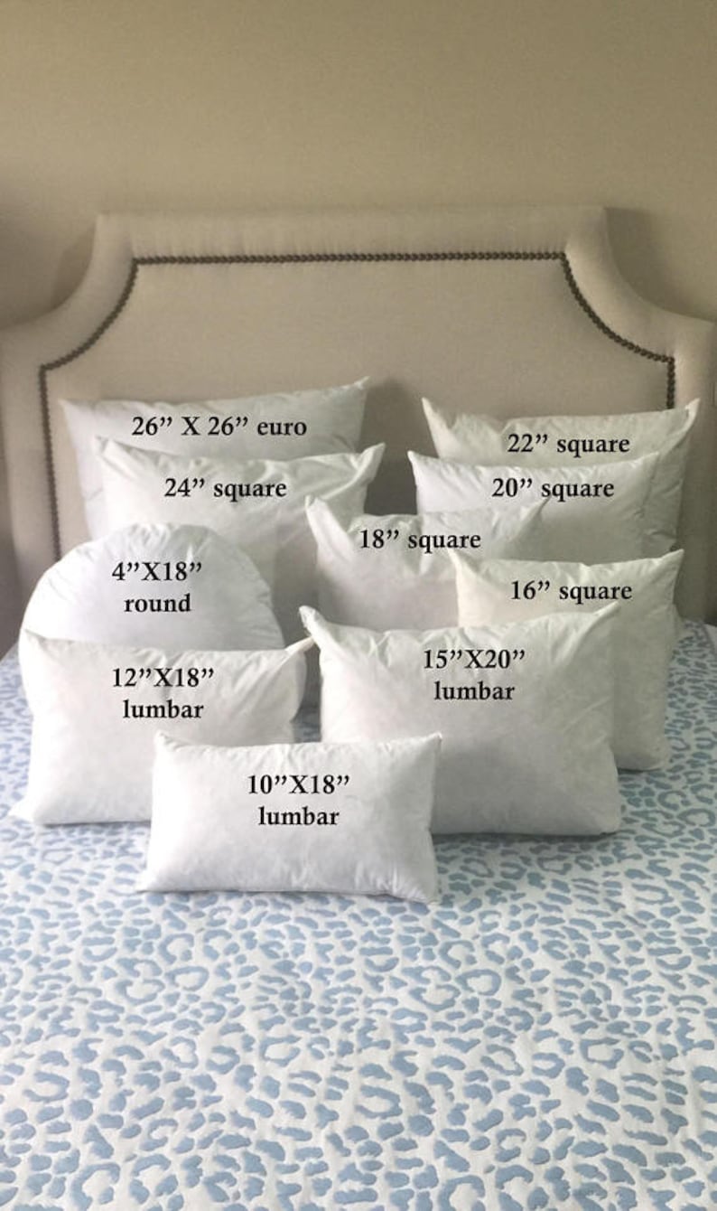 May include: A collection of white pillow inserts in various sizes and shapes, including square, round, and lumbar. The pillow inserts are arranged on a white and blue patterned bedspread. The sizes of the pillows are labeled in inches.