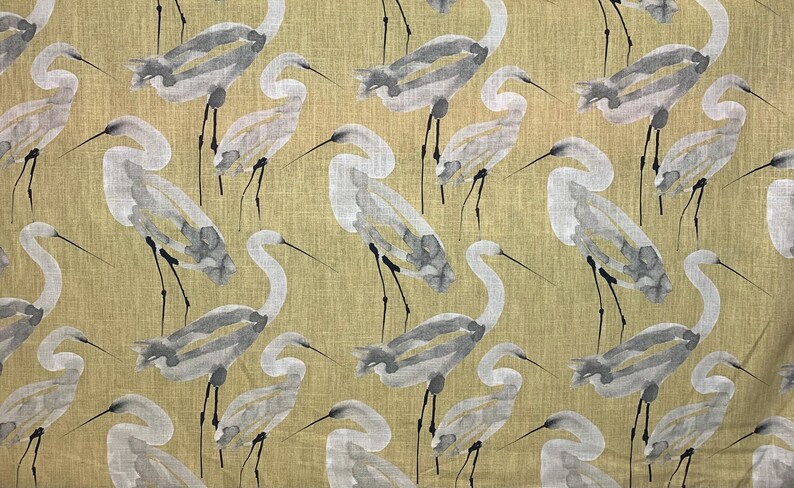 Pode incluir: Tecido com um padr&atilde;o repetido de gar&ccedil;as em aquarela em tons de cinza e branco sobre um fundo verde-oliva claro. As aves s&atilde;o retratadas com pesco&ccedil;os e pernas longas, criando um design inspirado na natureza.