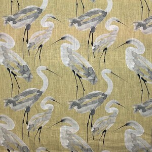 Pode incluir: Um tecido com um padr&atilde;o repetido de gar&ccedil;as em estilo aquarela em tons de cinza e branco. As aves s&atilde;o colocadas sobre um fundo verde-oliva claro. Os pesco&ccedil;os e pernas longas das gar&ccedil;as s&atilde;o vis&iacute;veis.