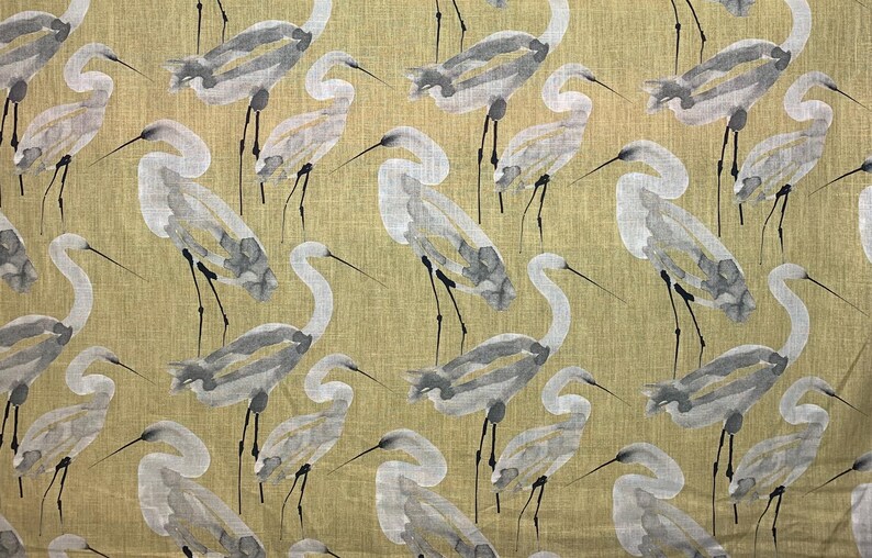 Pode incluir: Um tecido com um padr&atilde;o repetido de gar&ccedil;as em estilo aquarela em tons de cinza e branco. As aves s&atilde;o colocadas sobre um fundo verde-oliva claro. Os pesco&ccedil;os e pernas longas das gar&ccedil;as s&atilde;o vis&iacute;veis.