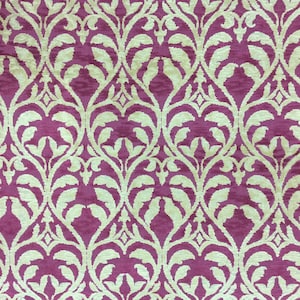 May include: A close-up of a fabric with a repeating pattern of white floral designs on a deep pink background.