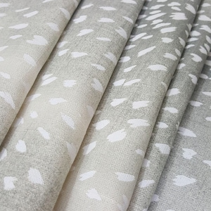 May include: Close-up of a folded fabric with a white and gray speckled pattern. The fabric has a subtle ombre effect, with the white specks becoming more prominent towards the lighter end.