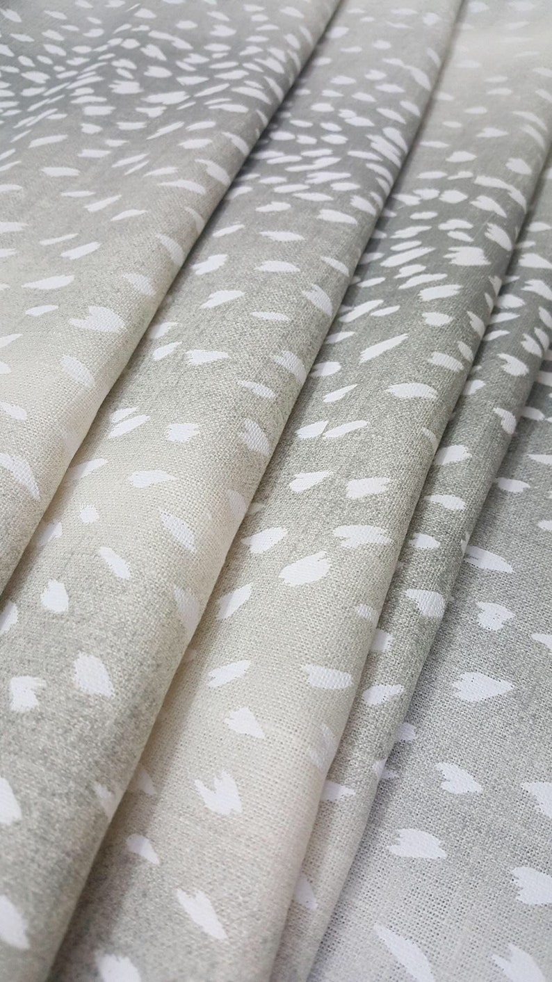May include: Close-up of a folded fabric with a white and gray speckled pattern. The fabric has a subtle ombre effect, with the white specks becoming more prominent towards the lighter end.