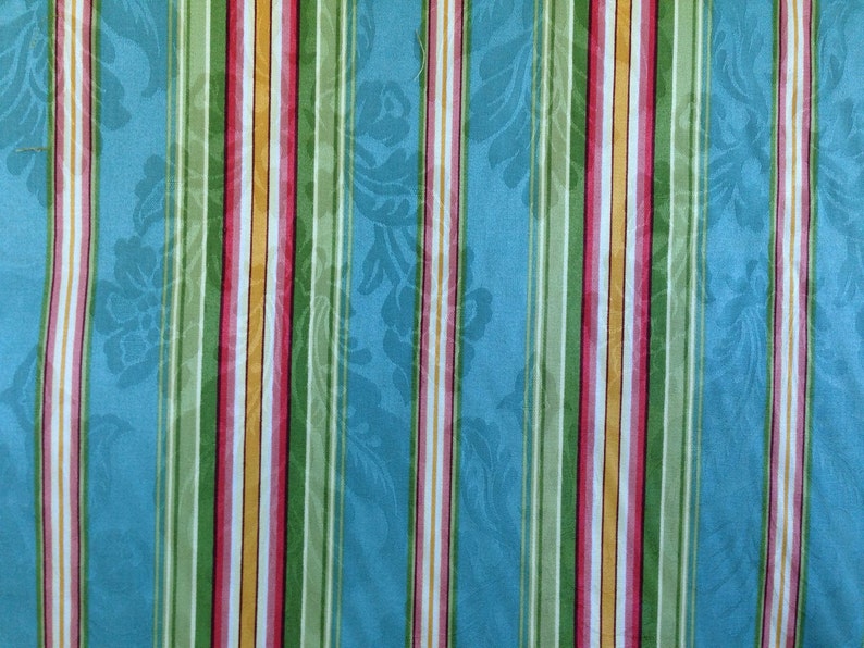 May include: A blue fabric with vertical stripes in green, pink, white, and yellow. The fabric has a subtle floral pattern.