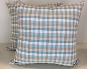 May include: Two square throw pillows with a light blue and brown plaid pattern.