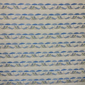 May include: A beige fabric with a repeating pattern of blue and white striped umbrellas and green lounge chairs.