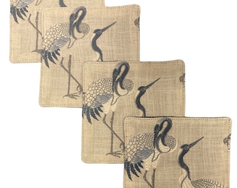 May include: Set of four beige linen coasters with a black and white crane design.