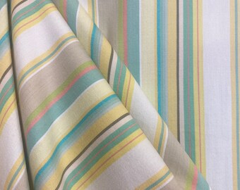 Può includere: Tessuto a righe in tonalità beige, giallo, azzurro e rosa. Il tessuto è piegato a metà, mostrando il motivo su entrambi i lati.