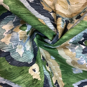 May include: Green, blue, and beige fabric with an abstract, ikat-style pattern. The fabric is folded and shows the texture of the material.