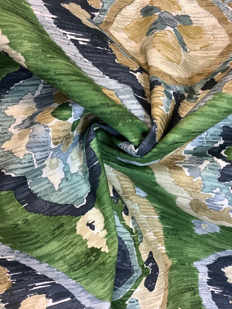May include: Green, blue, and beige fabric with an abstract, ikat-style pattern. The fabric is folded and shows the texture of the material.