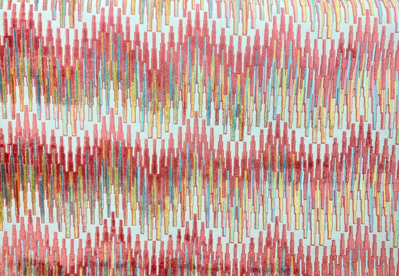 Op de afbeelding: Abstracte stof met een witte achtergrond en een herhalend patroon van verticale lijnen in tinten rood, oranje, geel, blauw en groen.
