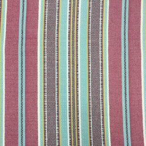May include: Striped fabric with alternating bands of red, white, blue, and yellow. The fabric has a woven texture.