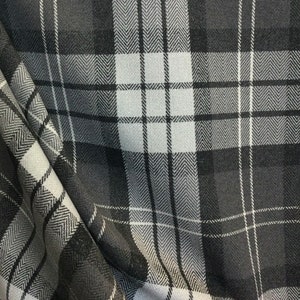 May include: A close-up of a black and white plaid fabric with a herringbone pattern. The fabric is soft and has a subtle sheen.