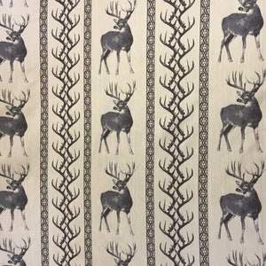 May include: Beige fabric with a repeating pattern of dark gray deer and stylized brown branches. The deer are facing right and have large antlers.