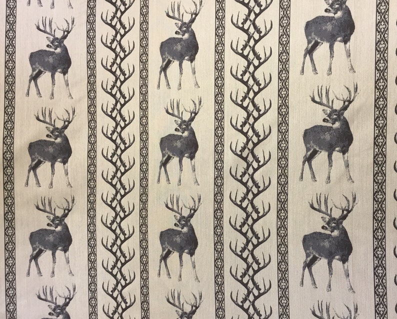 May include: Beige fabric with a repeating pattern of dark gray deer and stylized brown branches. The deer are facing right and have large antlers.