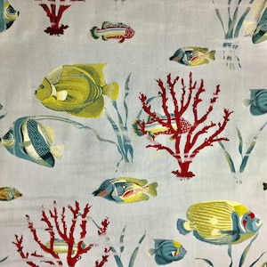 May include: A light blue fabric with a repeating pattern of yellow, blue, and red fish and coral. The fish are stylized and have a cartoonish appearance. The coral is red and has a branching shape.