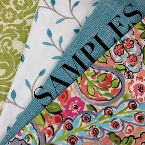 May include: Four fabric swatches, one with a green floral pattern, one with a white background and gray branches, one with a blue and green paisley pattern, and one with a solid blue color. The blue swatch has the word "SAMPLES" written in black.