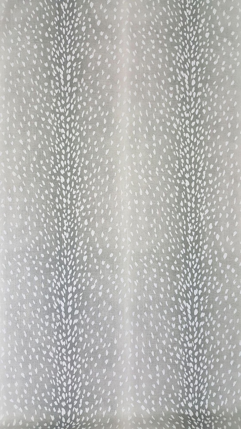 May include: A close-up of a gray fabric with a white spotted pattern. The fabric has a subtle texture and a soft, muted color.