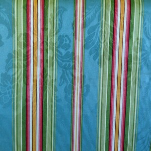 May include: Striped fabric with alternating blue, green, yellow, pink, and white stripes. The fabric has a subtle floral pattern.