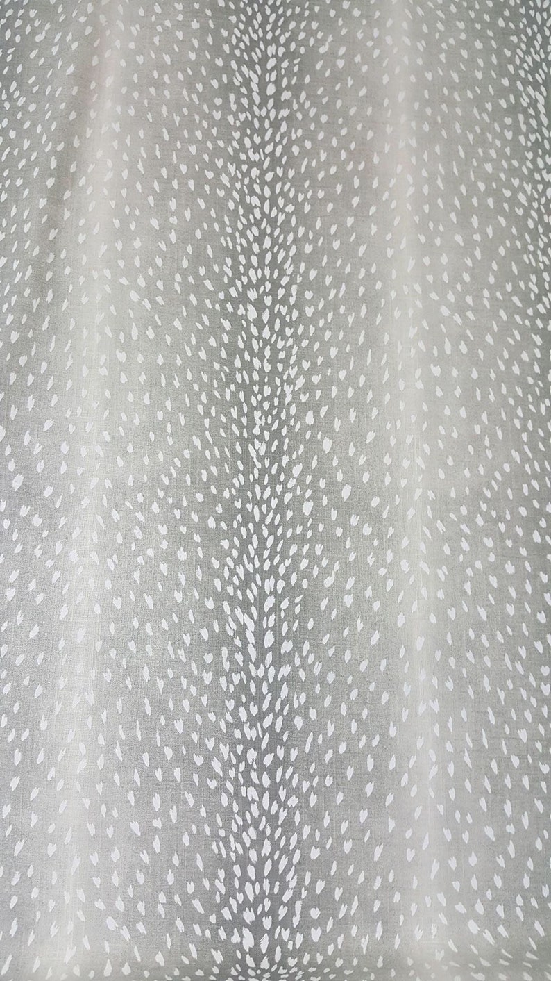 May include: A white fabric with a gray background featuring a repeating pattern of white spots. The spots are arranged in a staggered pattern, creating a subtle, textured look.