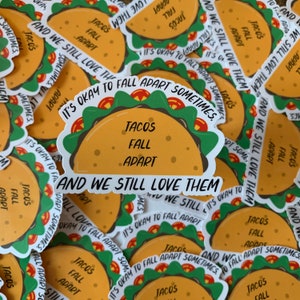K&ouml;nnte beinhalten: Nahaufnahme von mehreren bunten Aufklebern mit einem Taco-Design. Die Aufkleber zeigen den Text "Tacos Fall Apart Sometimes. And We Still Love Them."