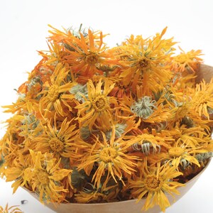 May include: A bunch of dried orange and yellow calendula flowers in a brown paper bag.