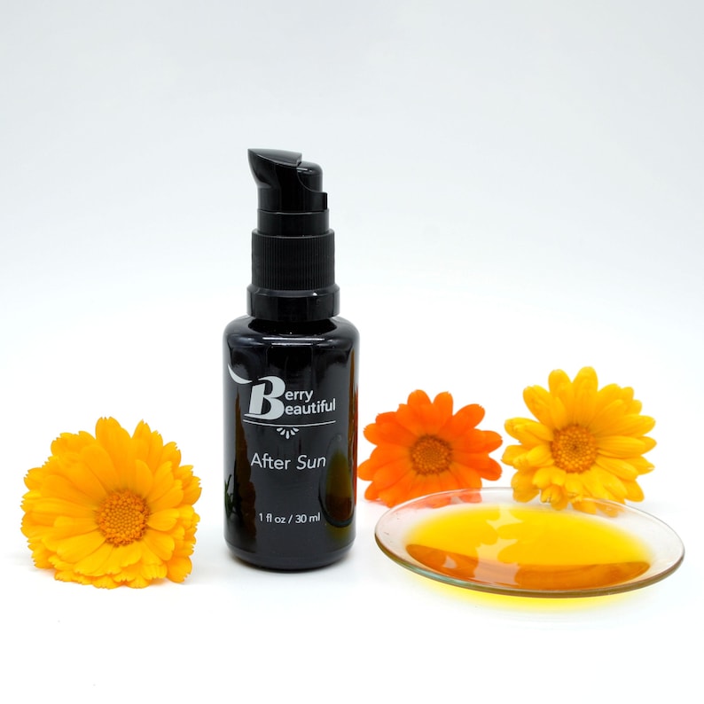 Berry Beautiful After Sun Serum in a Miron glass bottle with freshly picked golden and orange calendula flowers. A dish reveals the rich golden hue of calendula and vanilla-infused raspberry seed oil, crafted to soothe and hydrate sun-exposed skin