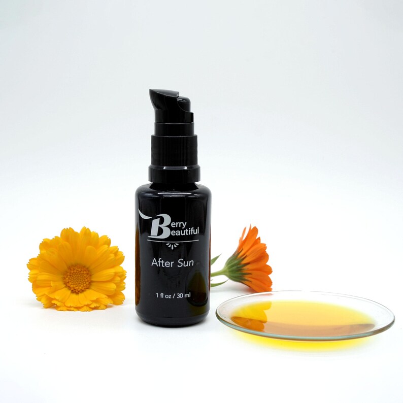 Berry Beautiful After Sun Serum in a Miron glass bottle, shown with hand-harvested calendula flowers and a clear dish highlighting the golden hue of calendula and vanilla-infused raspberry seed oil, a soothing botanical blend for after-sun care.