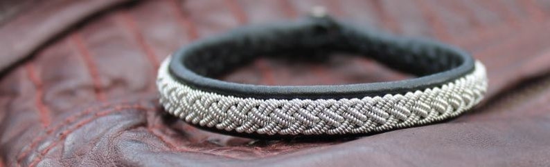 May include: A black leather bracelet with a silver braided design.