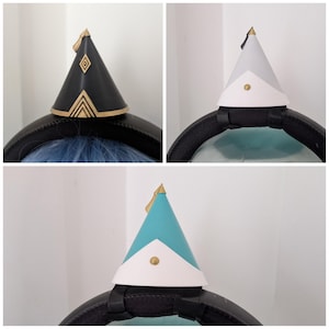 Può includere: Un set di tre accessori conici per cuffie, ognuno con un design distinto. Uno è nero con accenti geometrici dorati, uno è grigio chiaro con base bianca e uno è verde acqua con base bianca e un piccolo dettaglio a borchia dorata.