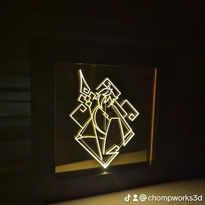 May include: A 3D printed light-up lamp with a geometric design featuring a stylised figure holding a weapon. The lamp is lit up in a warm yellow colour.