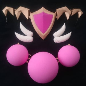 Peut inclure: Un ensemble d'accessoires de cosplay rose et or, comprenant un bouclier, deux cornes et trois sphères reliées par une chaîne dorée.
