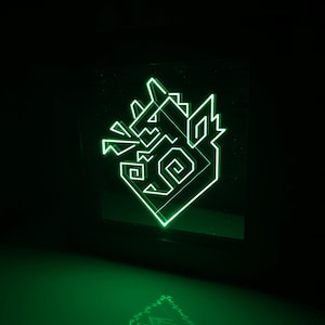 Pode incluir: Um design geométrico verde néon de uma cabeça de lobo, iluminado contra um fundo preto. A obra de arte apresenta ângulos agudos e um contorno brilhante estilizado, com um reflexo visível abaixo.