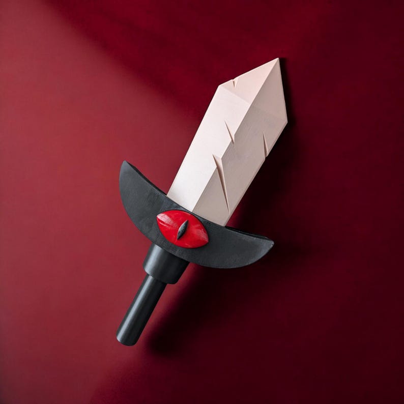 May include: A white sword with a black handle and a red eye design. The sword is made of paper and has a textured surface.