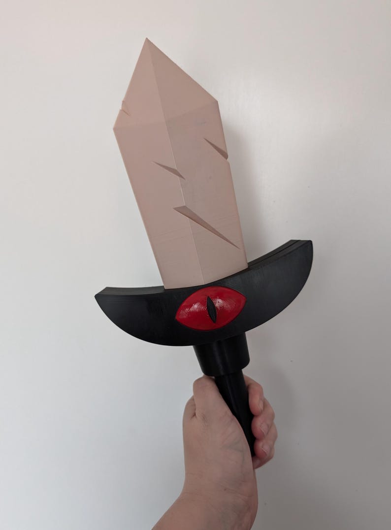 May include: A pink crystal sword with a black handle and a red eye design. The sword is held in a hand.