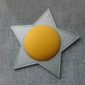 May include: A grey five-pointed star with a yellow circle in the centre.