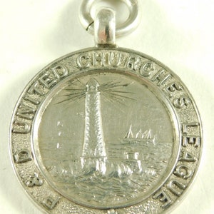 May include: Silver medal with a lighthouse and ships on the sea. The medal is inscribed "The United Churches League".