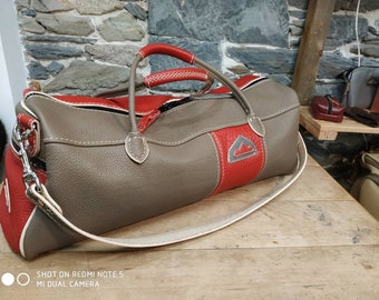 Duffel-shaped travel or sports bag in gray/taupe and red saddle leather