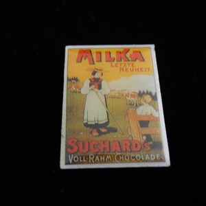 May include: A vintage Milka chocolate advertisement featuring a woman in traditional attire, holding a staff, in a pastoral scene. The advertisement has the text "MILKA LETZTE NEUHEIT" and "SUCHARD'S VOLL-RAHM CHOCOLADE" in red and orange lettering.