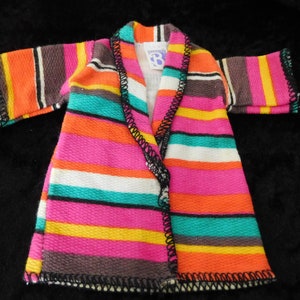 Könnte beinhalten: Eine gestreifte, mehrfarbige Robe mit schwarzem Besatz. Die Robe hat einen Kragen und ist aus einem weichen, strukturierten Stoff gefertigt.