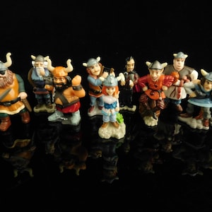 Könnte beinhalten: Eine Sammlung von 10 kleinen Plastikfiguren von Wikingerkriegern und einer weiblichen Figur. Die Figuren sind in verschiedenen Farben bemalt, darunter Rot, Blau, Grün und Braun. Sie tragen alle Helme und Rüstungen, und einige halten Waffen.