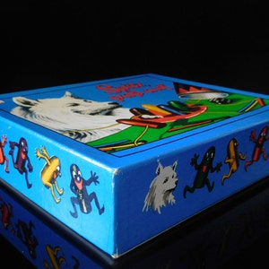 Puede incluir: Una caja azul con un perro blanco y personajes coloridos en la parte delantera. La caja tiene el texto "Catch the Bug" en la parte delantera.