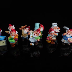 以下が含まれることがあります： シェフの帽子をかぶり、さまざまなキッチン用品を持っている、小さなカラフルなノームの置物10個セット。ノームはすべて赤い帽子をかぶり、白いひげを生やしています。置物はプラスチック製で、高さは約7.5cmです。