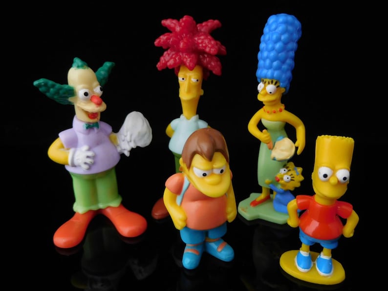 Pode incluir: Um conjunto de seis figuras de personagens dos Simpsons. As figuras s&atilde;o feitas de pl&aacute;stico e s&atilde;o coloridas de forma brilhante. Os personagens incluem Bart, Lisa, Homer, Marge, Krusty o Palha&ccedil;o e um personagem amarelo com uma camisa vermelha.